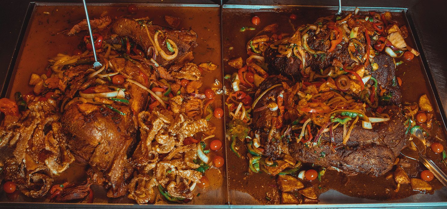 Trays of roast meats with peppers and onions on the carvery line