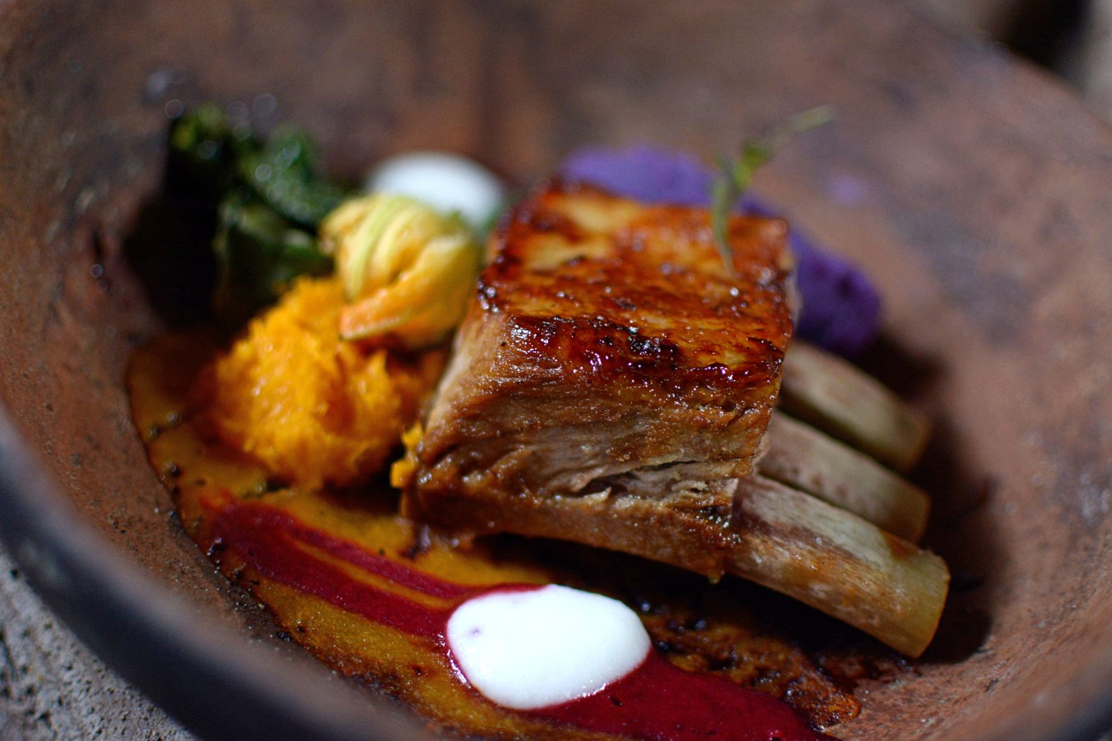 A basted pork rib plated with roast vegetables